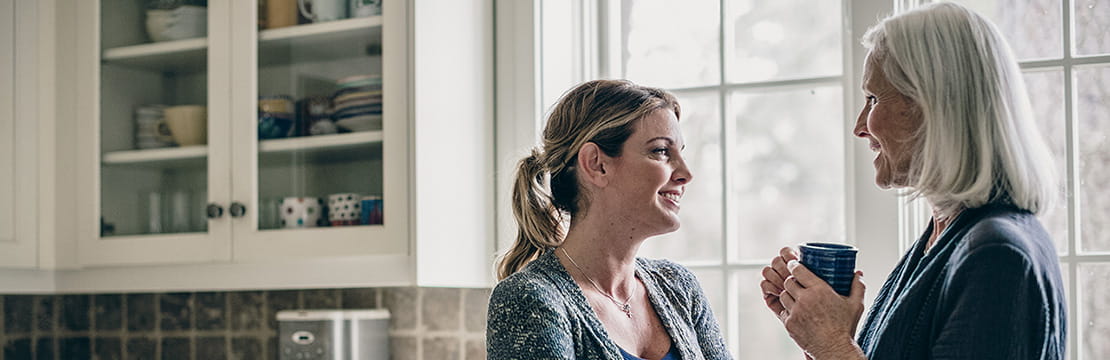 Mother and daughter having coffee in kitchen
