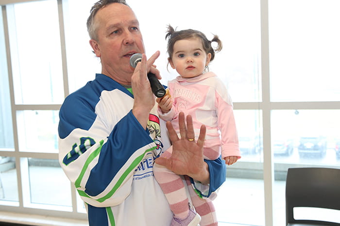 Man holding a child and speaking into a microphone
